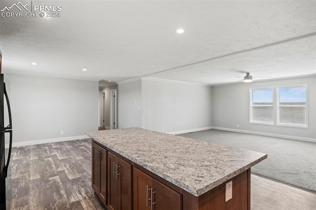 kitchen with a textured ceiling, crown molding, a center island, and dark hardwood / wood-style floors