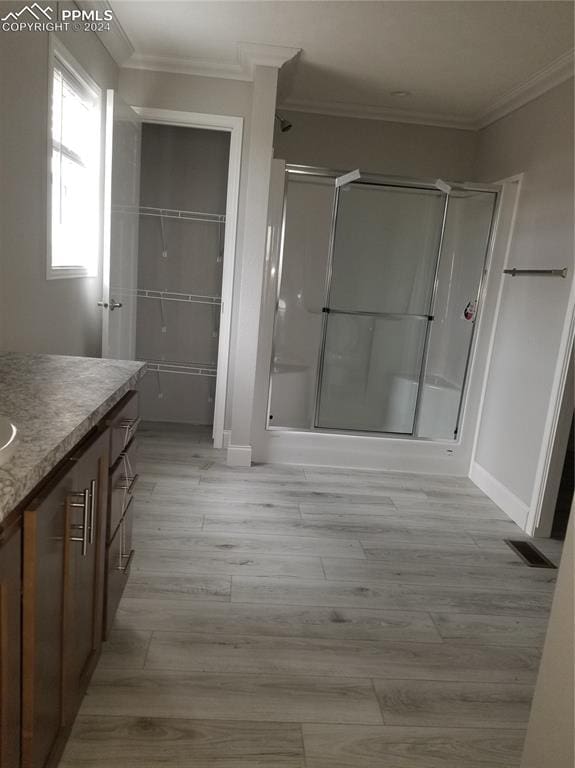 bathroom featuring hardwood / wood-style floors, vanity, a shower with door, and crown molding