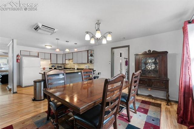 dining space with light hardwood / wood-style flooring, sink, and an inviting chandelier