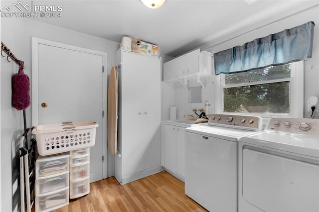 washroom with light wood-type flooring, cabinets, and separate washer and dryer