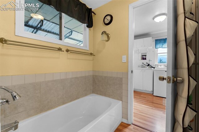 bathroom featuring a bathing tub, hardwood / wood-style floors, and washer and dryer