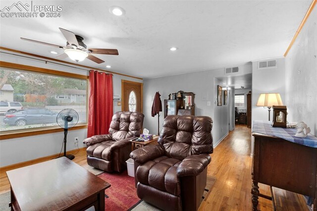 living room featuring light hardwood / wood-style flooring, crown molding, and ceiling fan