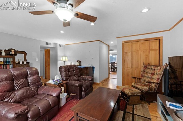 living room featuring ceiling fan, ornamental molding, and light hardwood / wood-style floors