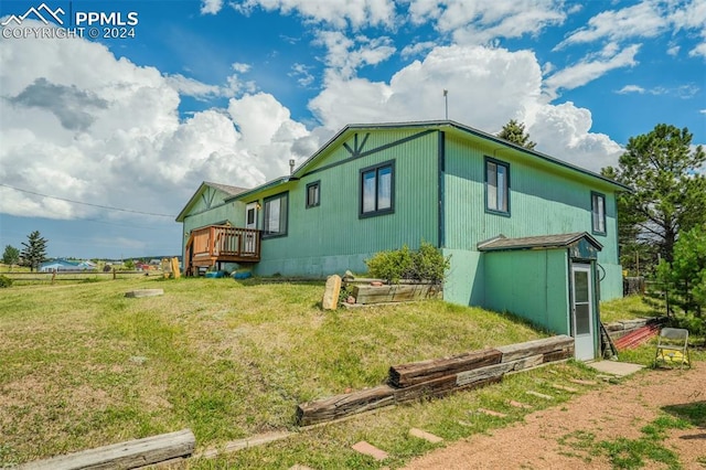 view of side of home featuring a yard and a deck