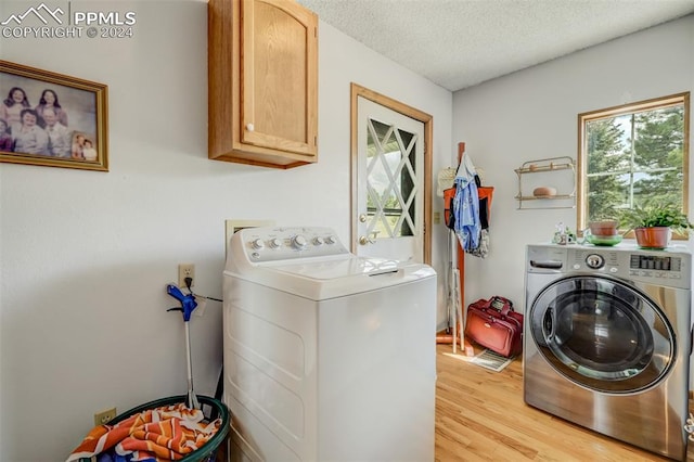 washroom featuring cabinets, a textured ceiling, light hardwood / wood-style floors, and washing machine and dryer