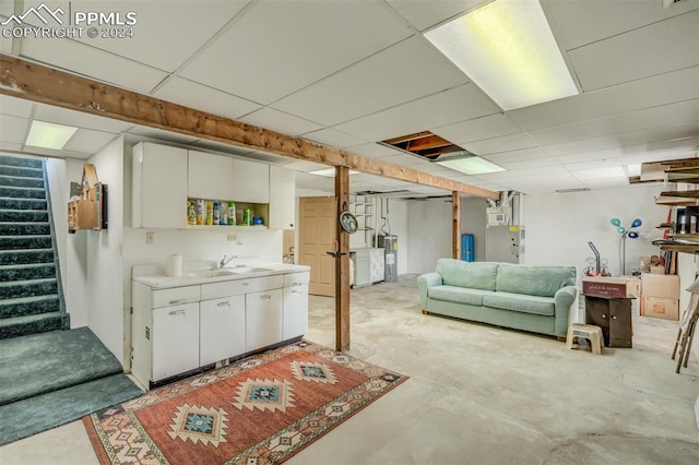 basement with a paneled ceiling, sink, and water heater