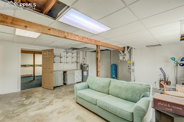 basement with a paneled ceiling and electric water heater