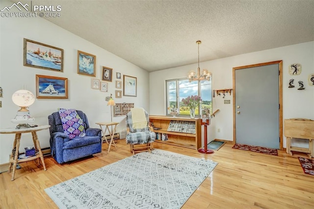 living area featuring an inviting chandelier, hardwood / wood-style flooring, lofted ceiling, and a textured ceiling