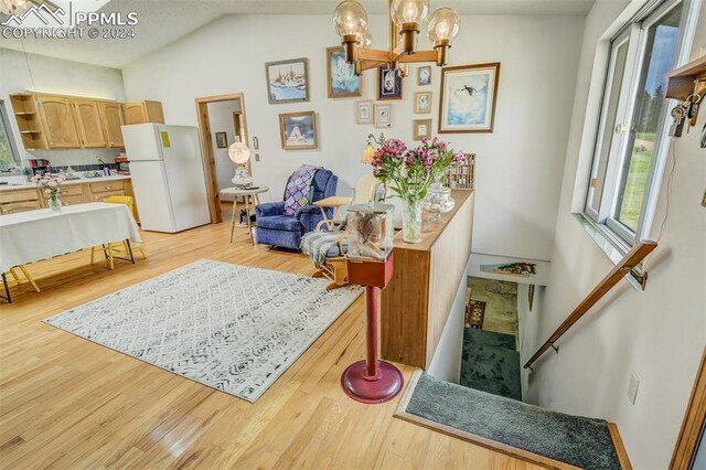 sitting room with vaulted ceiling, an inviting chandelier, and light hardwood / wood-style floors