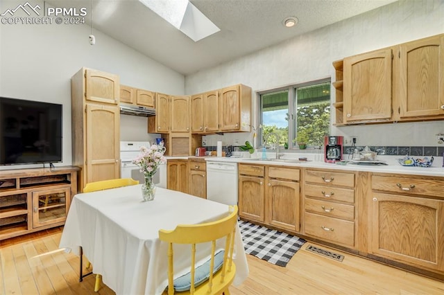 kitchen with sink, white appliances, lofted ceiling with skylight, light brown cabinetry, and light hardwood / wood-style floors