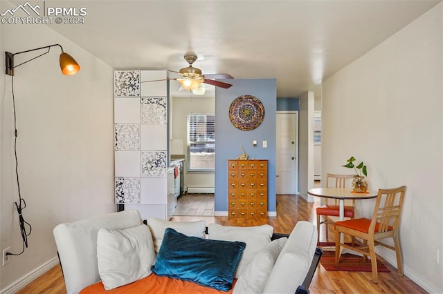 dining space with a baseboard heating unit, ceiling fan, and light hardwood / wood-style floors