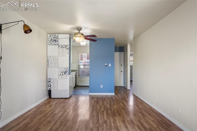 unfurnished bedroom with dark wood-style floors, baseboard heating, a ceiling fan, and baseboards