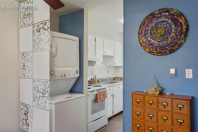 kitchen featuring white electric range oven, white cabinetry, sink, stacked washer and clothes dryer, and decorative backsplash