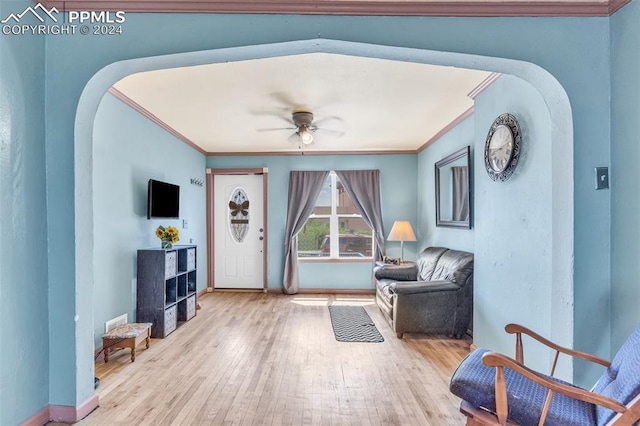 living area featuring hardwood / wood-style floors, ornamental molding, and ceiling fan