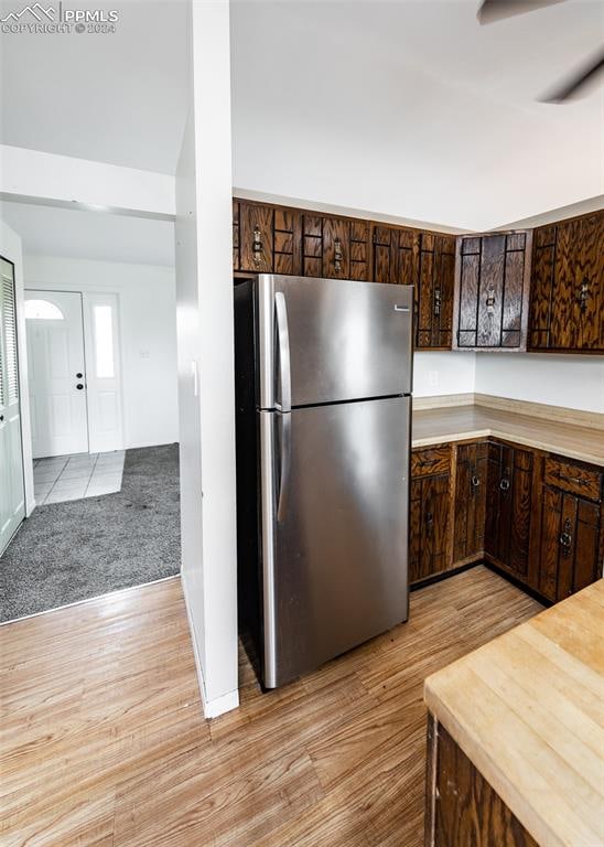 kitchen featuring dark brown cabinets, light hardwood / wood-style floors, and stainless steel fridge