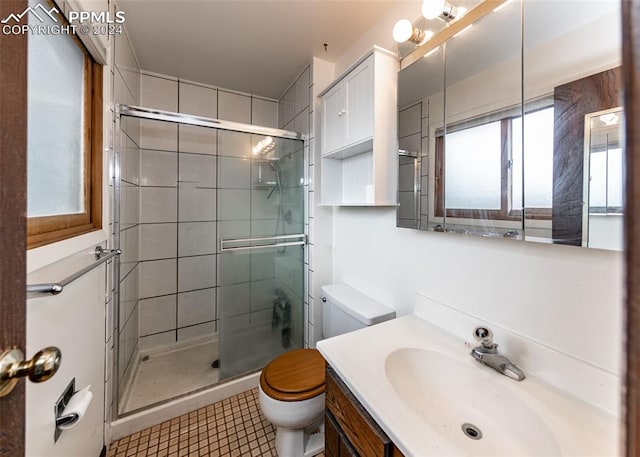 bathroom with vanity, a shower with door, toilet, and tile patterned flooring