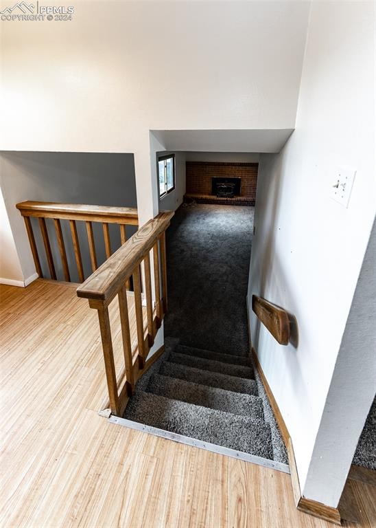 staircase with a fireplace and hardwood / wood-style flooring