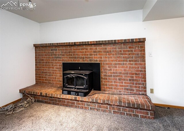 interior details with a wood stove, a fireplace, and carpet floors