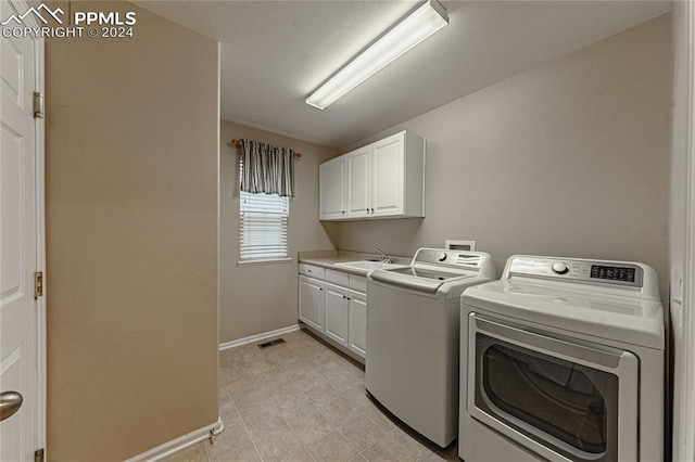 clothes washing area featuring separate washer and dryer, cabinets, and sink