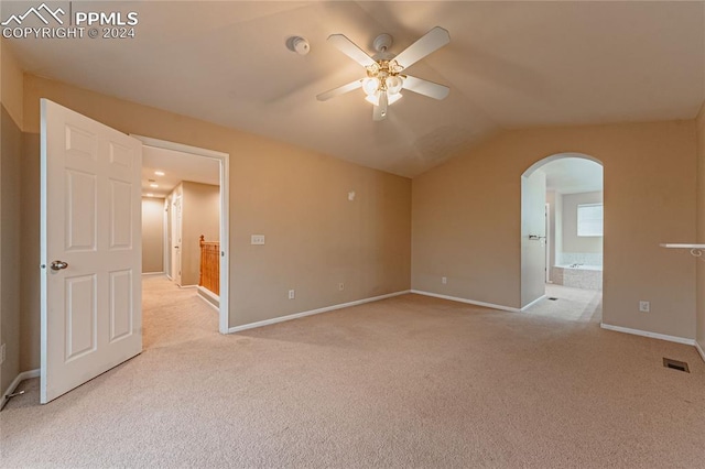 spare room with ceiling fan, light carpet, and vaulted ceiling