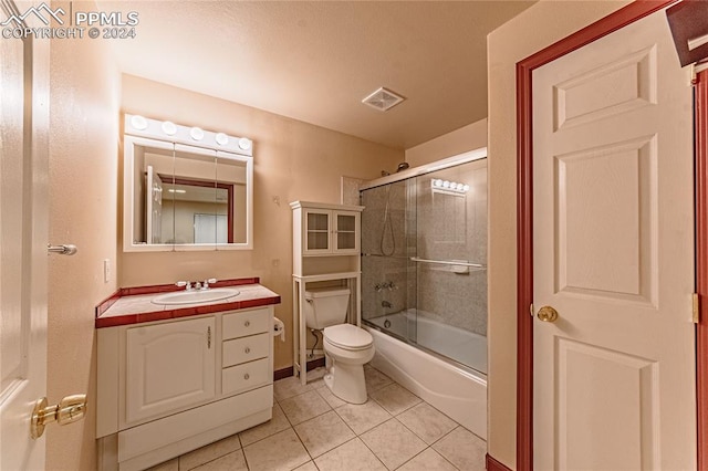 full bathroom featuring combined bath / shower with glass door, vanity, toilet, and tile patterned floors