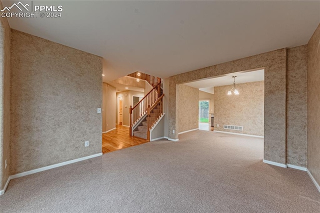 empty room with carpet and a notable chandelier