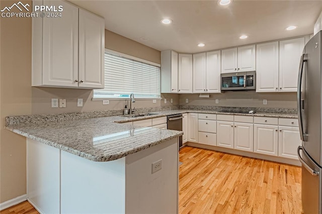 kitchen featuring white cabinets, appliances with stainless steel finishes, light hardwood / wood-style floors, sink, and kitchen peninsula