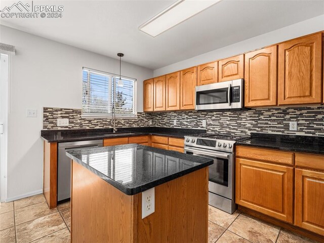 kitchen with decorative backsplash, appliances with stainless steel finishes, pendant lighting, light tile patterned flooring, and a kitchen island