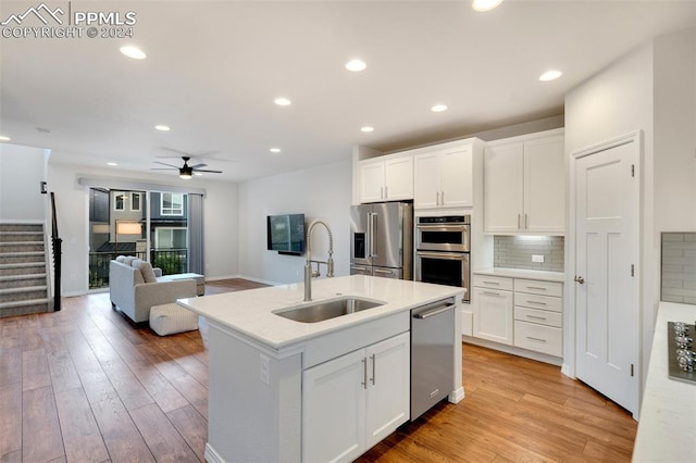 kitchen with ceiling fan, backsplash, light hardwood / wood-style floors, sink, and stainless steel appliances