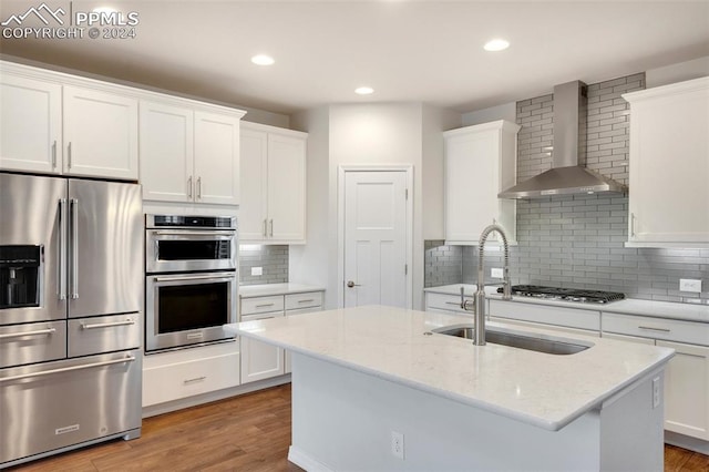 kitchen featuring light hardwood / wood-style floors, backsplash, stainless steel appliances, and wall chimney exhaust hood