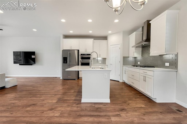 kitchen with decorative backsplash, wall chimney exhaust hood, a kitchen island with sink, hardwood / wood-style floors, and stainless steel appliances