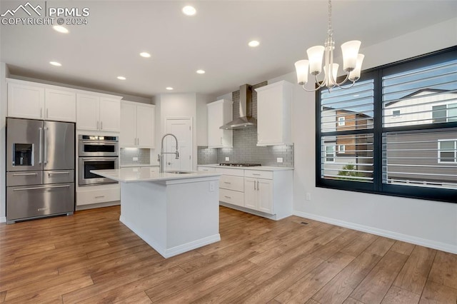 kitchen with sink, light wood-type flooring, wall chimney exhaust hood, decorative backsplash, and stainless steel appliances