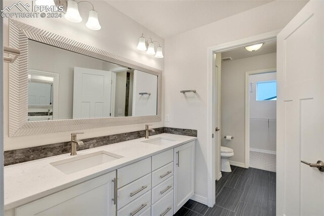 bathroom with tile patterned floors, toilet, backsplash, and dual bowl vanity