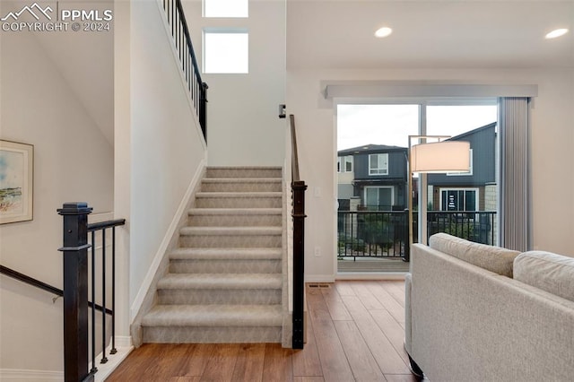 stairs with hardwood / wood-style floors and a towering ceiling