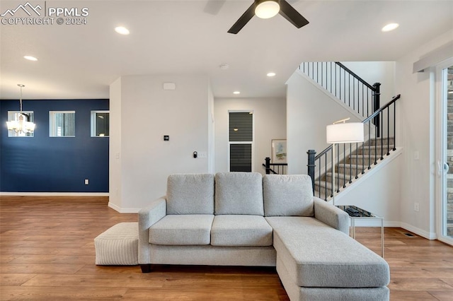 living room featuring ceiling fan with notable chandelier and wood-type flooring