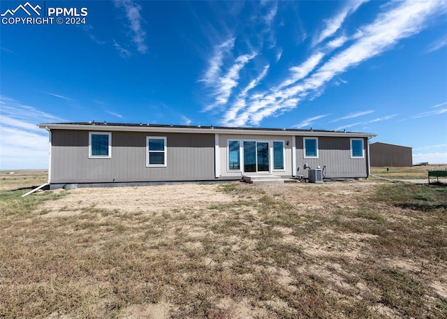 rear view of property featuring cooling unit and a yard