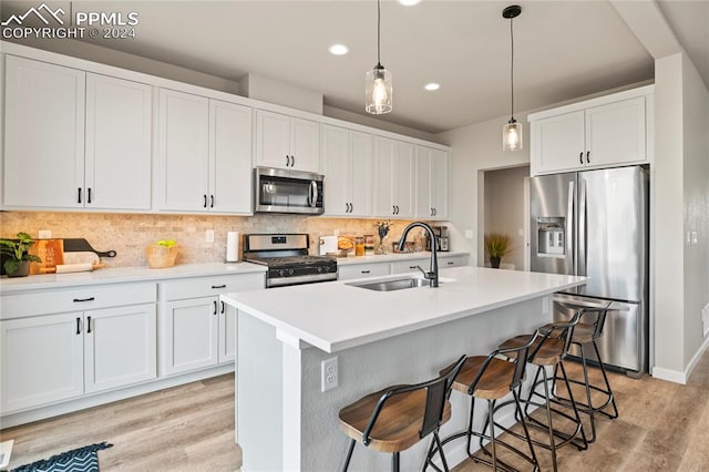 kitchen with appliances with stainless steel finishes, sink, light wood-type flooring, and backsplash