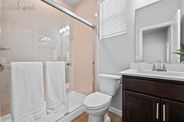 bathroom with hardwood / wood-style flooring, vanity, toilet, and walk in shower