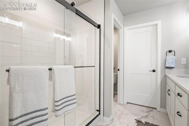 bathroom featuring a shower with shower door, vanity, tile patterned flooring, and toilet