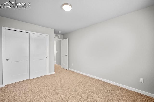 unfurnished bedroom with a closet and light colored carpet