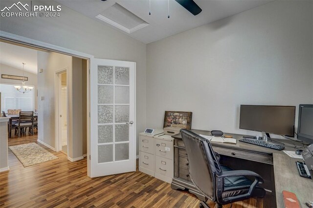 office with vaulted ceiling, ceiling fan with notable chandelier, and hardwood / wood-style floors