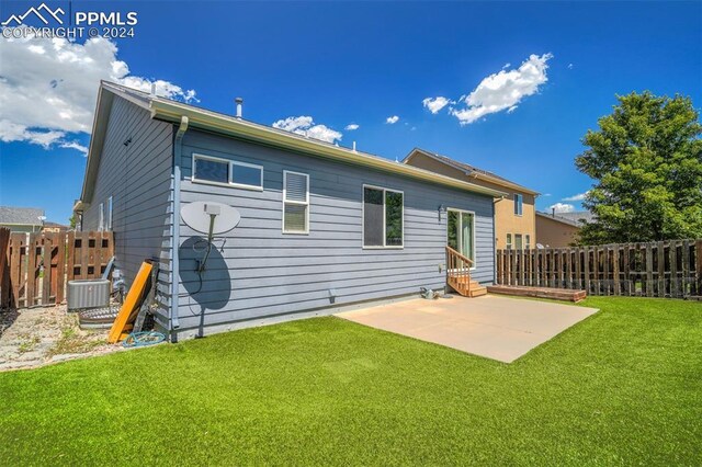 back of house with cooling unit, a patio area, and a yard