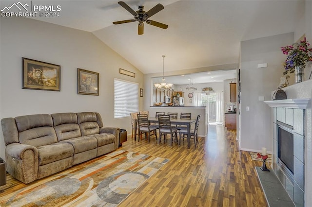 living room with ceiling fan with notable chandelier, vaulted ceiling, and hardwood / wood-style floors