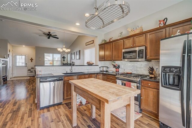 kitchen featuring sink, kitchen peninsula, appliances with stainless steel finishes, and wood-type flooring