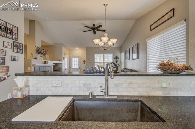 kitchen with sink, vaulted ceiling, and ceiling fan with notable chandelier