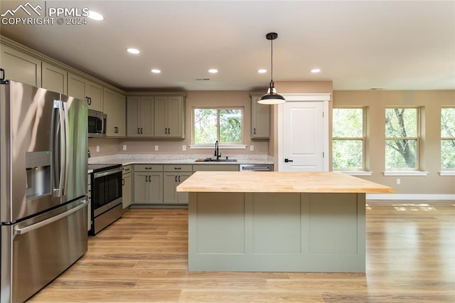 kitchen with light wood-type flooring, wooden counters, a healthy amount of sunlight, and stainless steel appliances