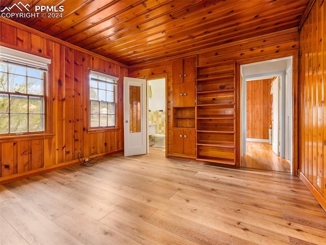 unfurnished room with wood walls, light wood-type flooring, and wood ceiling