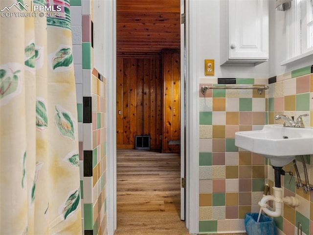 bathroom with hardwood / wood-style floors and tile walls