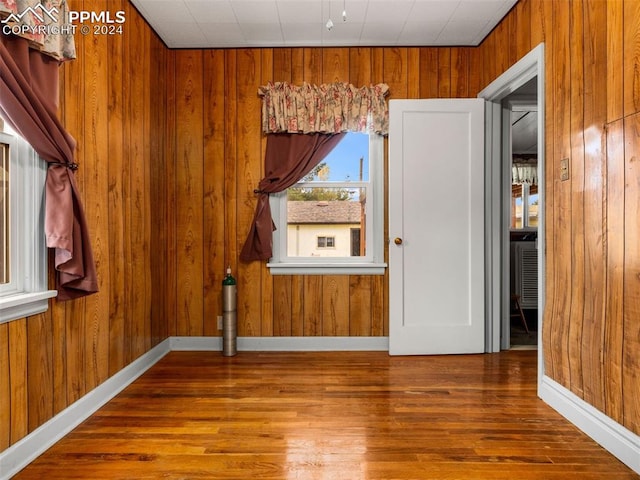 empty room featuring hardwood / wood-style flooring and wooden walls