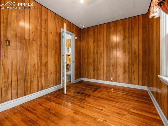 unfurnished room featuring hardwood / wood-style floors and wood walls